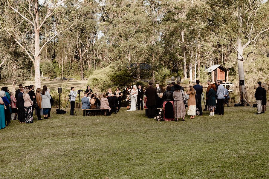 ceremony at bawley vale estate with some guests standing anf some sitting