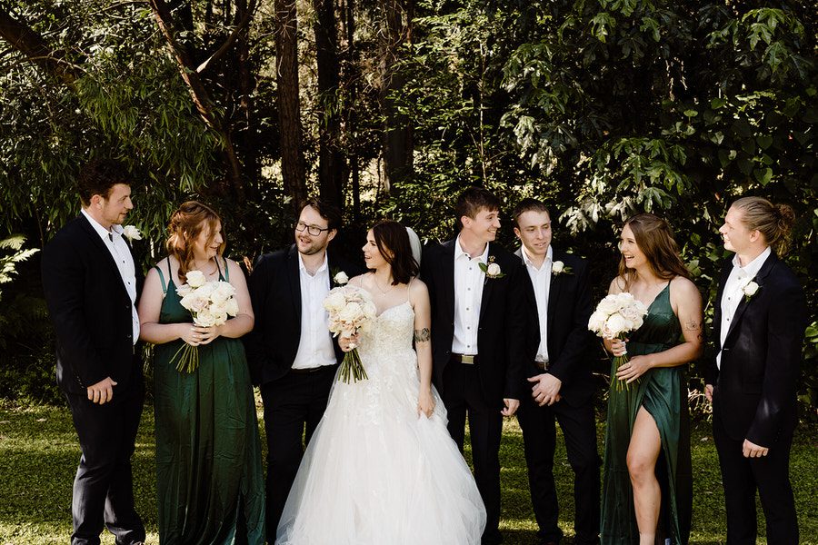 Kayleigh & Michael with their bridal party chatting for a photo.They are standing in front of gum trees. 