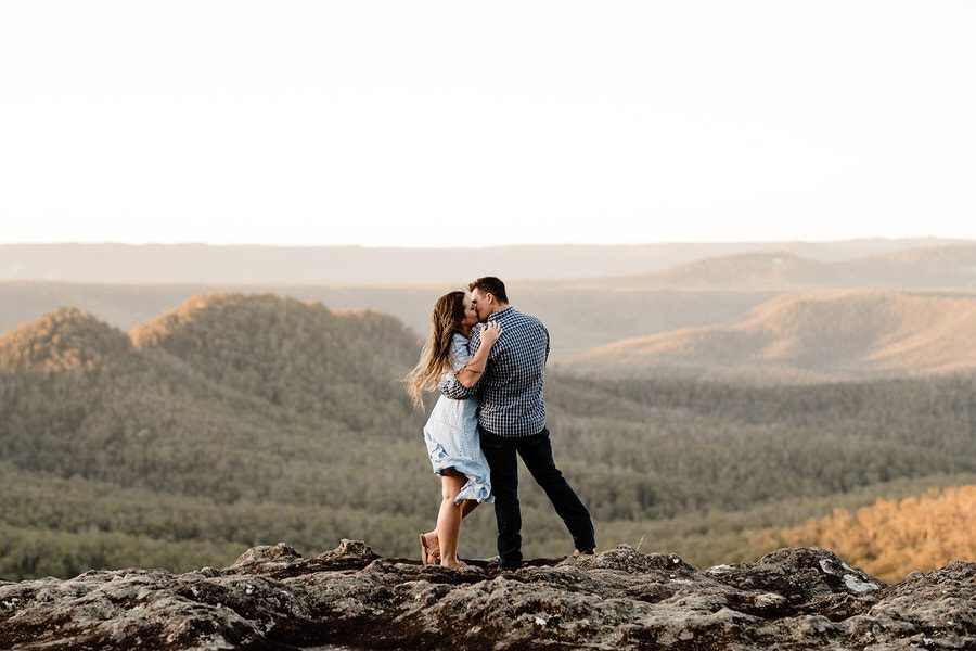 engagement photoshoot at Mckenzies lookout. Couple standing on cliff looking over the valley