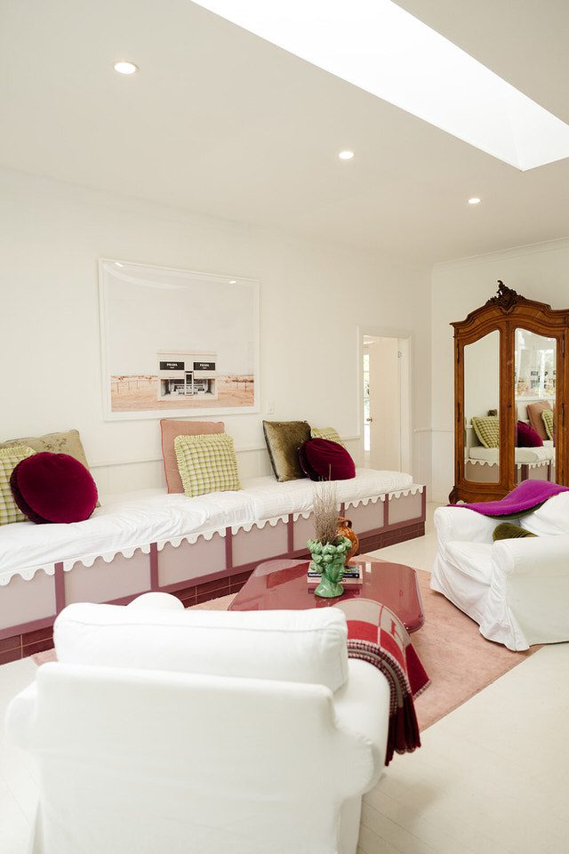 The lounge room inside the on-site accommodation at The Merribee, featuring white slipcovered armchairs, a long daybed, and curated styling under a skylight.
