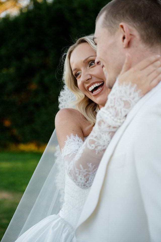 Bride laughing with her groom at sunset at The Merribee, with her arm around his neck and her veil catching the late afternoon light.